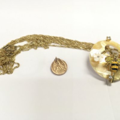 A costume bee and honey comb pendant on chain and a small gold medallion.