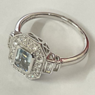 Platinum art deco style ring set with central step cut aquamarine and RBC and baguette cut diamonds. Aquamarine 0.82ct. Diamonds 0.60ct. Postage category A.