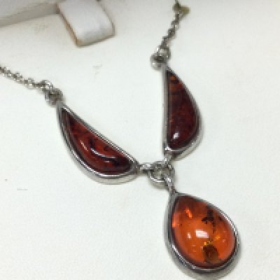 An Amber and silver necklace . Postage category A