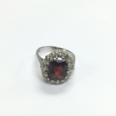 An 18ct gold ring set with a central garnet surrounded by diamonds, approx 6g and approx size N. Shipping category A.