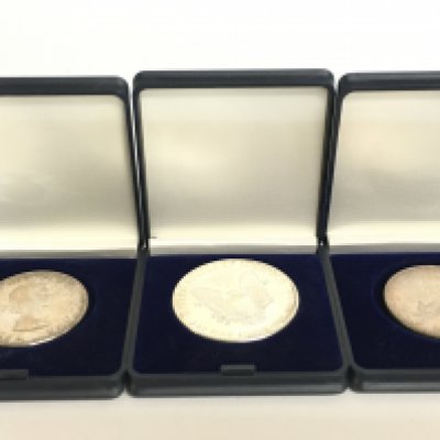 A silver 1oz American dollar and two 1963 Canadian dollars. Postage category A