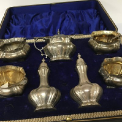A case containing a silver condiment set a set of four salt cellars mustard pot and pepper pots Sheffield 1904 hallmarks.