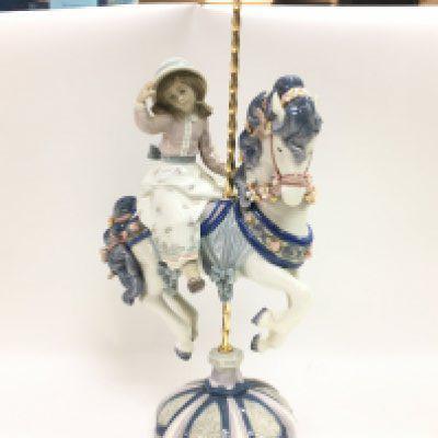 A Lladro girl on a carousel horse porcelain figure. Some flowers missing however no obvious large damage or restoration. 42cm tall. This lot cannot be posted