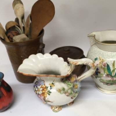 A Victorian stoneware jar containing a collection of antique wooden treen vernacular spoons a conforming stoneware cooking pot a Poole vase and two decorative jugs.