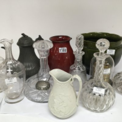 A collection of decanters a green glazed jardiniere and other ornaments.
