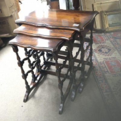 A nest of three mahogany occasional tables with shaped tops on turned supports.