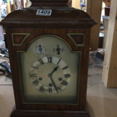 A collection of three mantle clocks with silver dials and Roman numerals.