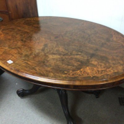 A quality Victorian burr walnut inlaid loo table the oval hinges top on a carved base with scroll feet and a set of six Victorian dining chairs with cabriole legs. Table top messures 135cmx103 cm