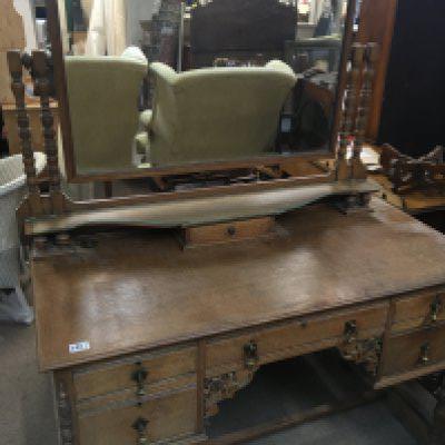 An oak dressing table with a raised mirrored back above drawers with blinded fretwork.