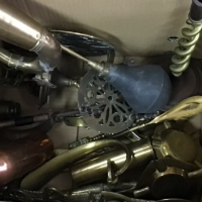 A box containing a collection of brass and copper including a vintage car horn candle sticks ammunition cases and other oddments.