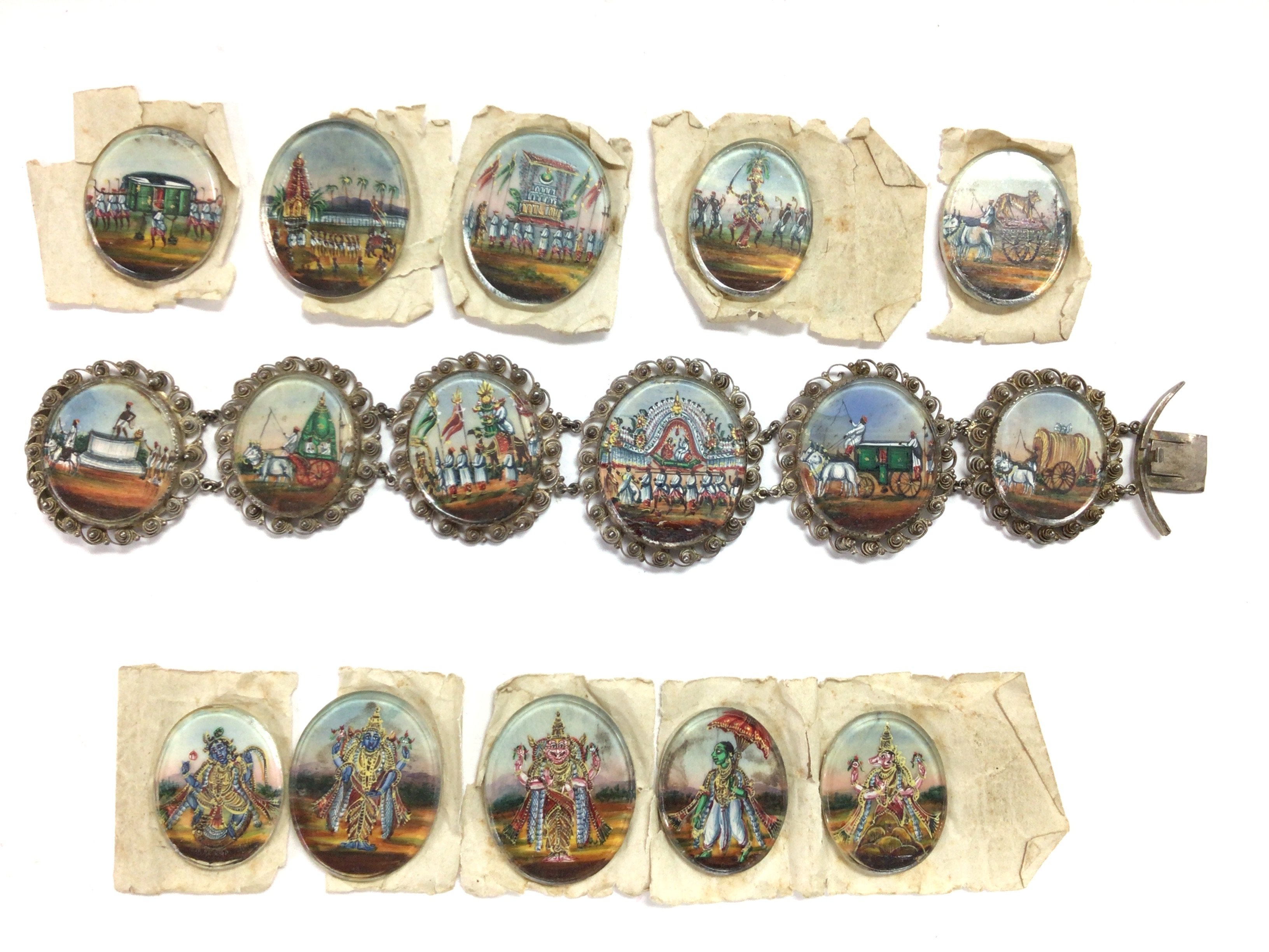 A 19th century collection of 16 minutes paintings with scenes depicting an Indian Royal wedding procession, 6mounted in a white metal filigree design bracelet each varying in size approximately 2.4 x 2.7cm. Painting scenes include 5 Indian deity&rsquo;s. Bracelet length 19cm. All paper mounted Postage B