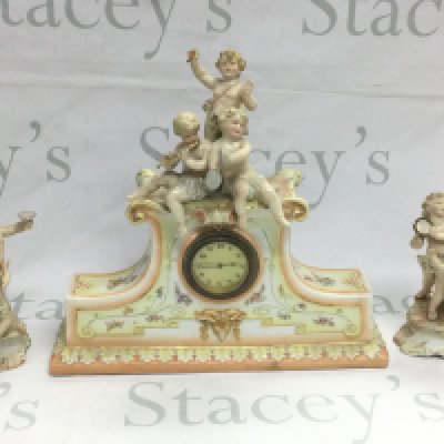 A Continental porcelain mantle clock surmounted with three cherubs and a pair of cherub clock garnitures (3). Shipping category D.