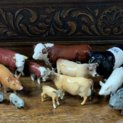 A collection of Beswick and Royal Doulton ceramic pigs and cows.