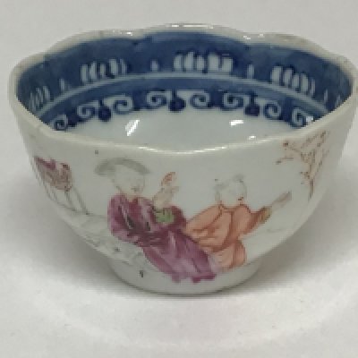 An 18th century Chinese Export porcelain tea bowl with a shaped edge the sides painted with figures in a windowed landscape. Slight hairline crack very minor chip to the rim.