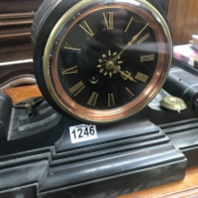 A Victorian slate mantle clock of classical form the circular dial with Roman numerals, with pendulum.