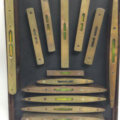 A framed collection of vintage brass topped spirit levels. This lot cannot be posted