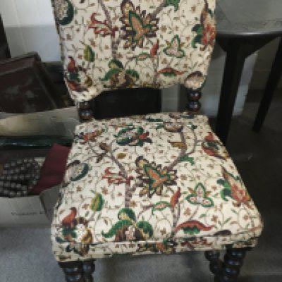 A carved stool and an upholstered oak chair
