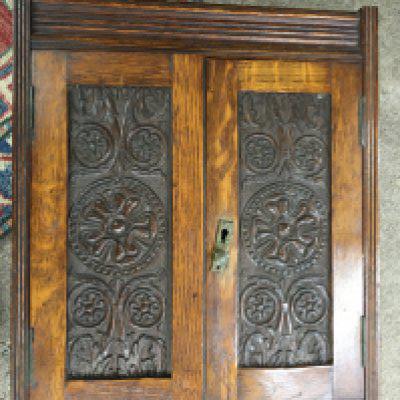 An oak small wall cabinet with carved design front panels , 45cm tall
