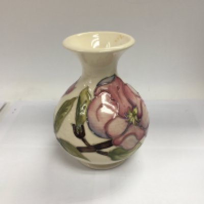 A Moorcroft hibiscus vase decorated with flowers and foliage.