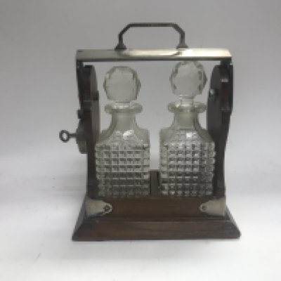 Two small tantalus decanters bottles with in a lockable cradle.