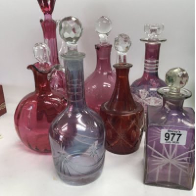 A collection of coloured decanters including some cut glass examples.