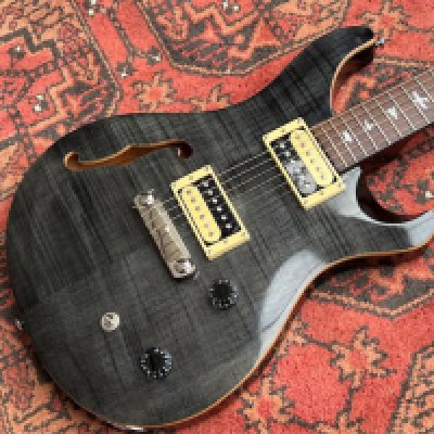 This is a PRS SE Custom 22 Semi Hollow electric guitar in Charcoal with flame maple top. It is largely unplayed with factory plastic on rear control cavity. Comes with rosewood finger board with birds. Missing switch tip. Comes with PRS Gigbag