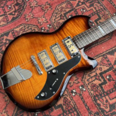 This is a Supro Hampton Flamed Maple Electric Guitar from 2017 in very good condition - largely unplayed with the factory plastic on the pickguard, the very light marking in the cutaways suggests very light playwear. Comes with Supro Branded GigBag