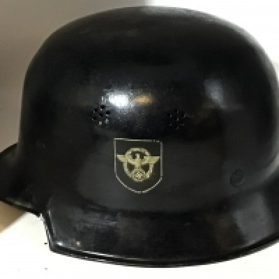 World War II German civil police helmet, black painted steel with police emblem decal affixed to the left side, a mobile swastika on a red shield decal affixed to the right side. There are two vent holes on either side, and the black paint on the helmet in good original condition helmet bears a black leather chin strap and leather liner very slight split on one side has interior stamp markOverall very good.
