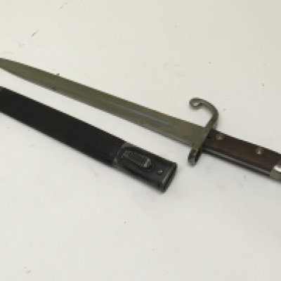 A German bayonet possible 1902 pattern with a hook quilon steel and wood grip. Leather and steel scabbard makers name stamped on the blade Weyersberg Kirschbaum & Co Solingen. Length 46cm