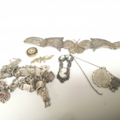 A Silver charm bracelet a 9carat gold brooch weight 1.3g other white metal and silver jewellery and an oval locket.