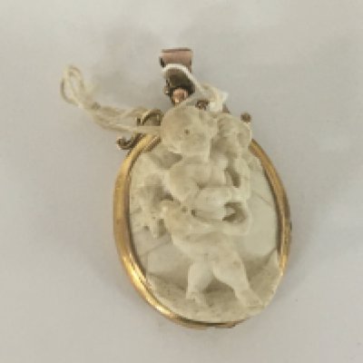 A Victorian three dimensional carved white stone pendent in the form of a winged cherub in a 9carat gold mount. 5cm in length.