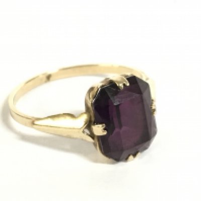 A 9 carat gold ring set with a purple gemstone, size O. 2g. Postage category a