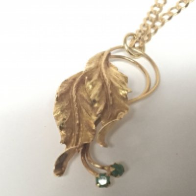 An 18carat gold brooch of folate design set with green emerald weight 6g approximately attached a 9carat gold open link necklace weight 9g approximately.