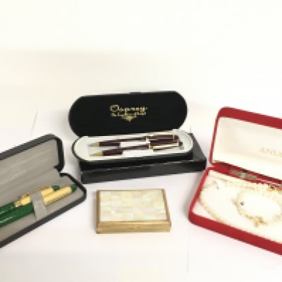 A collection of cased pens, a compact mirror and a simulated pearl necklace. Postage category C