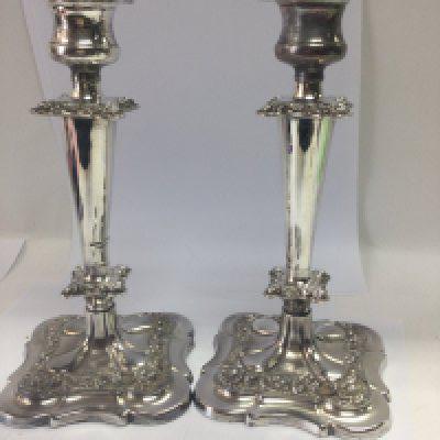 A box of silver plated ware including a pair of candle sticks and two silver wine labels.