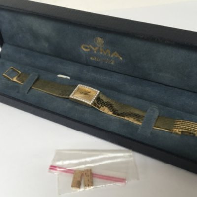 A ladies 14 carat gold watch CYMA the gold watch with a rectangular dial set with a row of brilliant cut diamonds the watch seen working and very lightly worn has two extra links in a fitted box. Watch total weight 37.5g including the extra links. With outer box.
