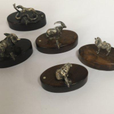 A set of eight quality 20th Century silver menu holders cast in the form of African animals on polished hardwood bases each inset with a small silver makers tablet. (5)