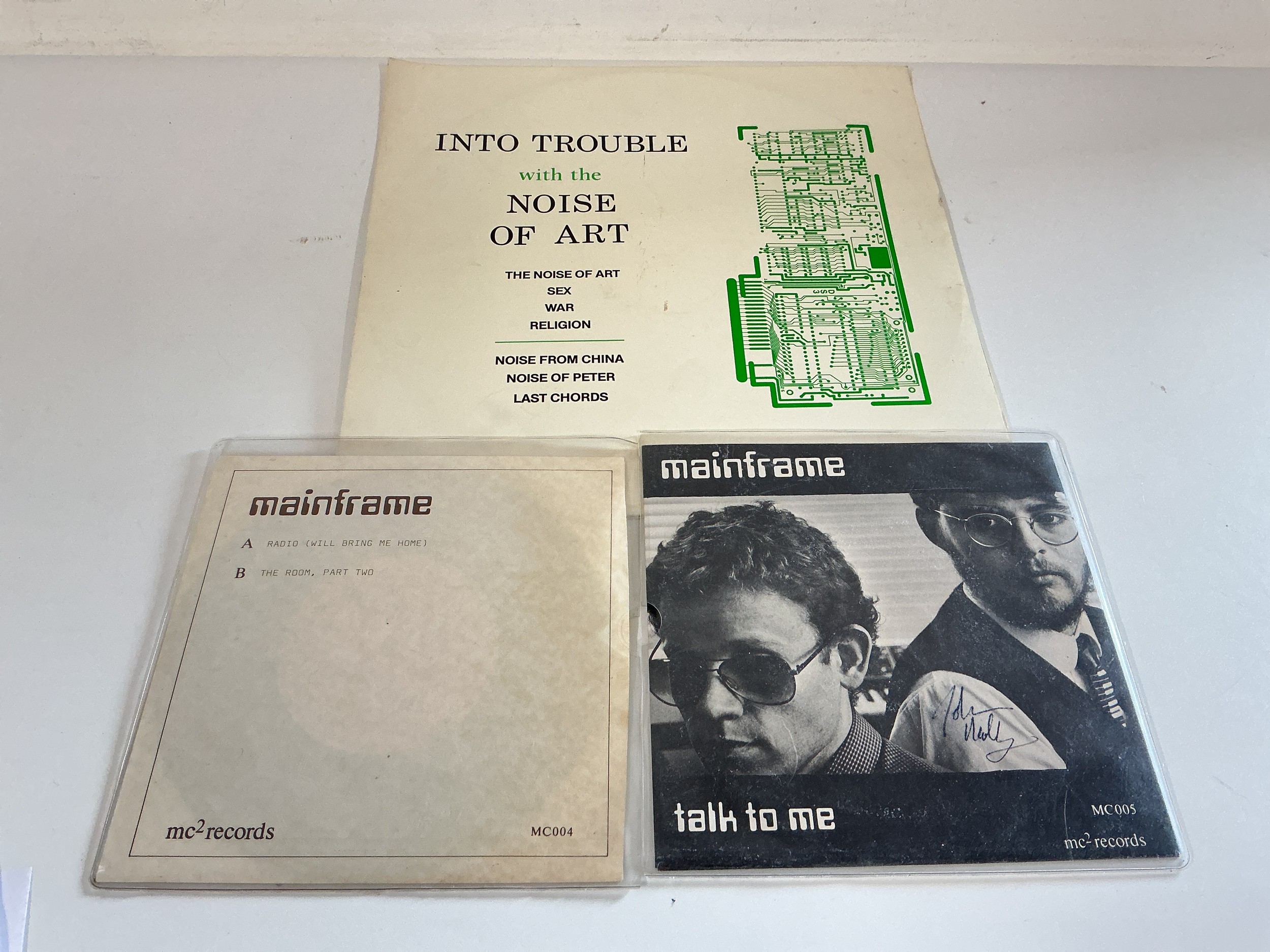 A Mainframe 7" single signed by John Molloy plus one other and an Into Trouble With The Noise Of Art 12" single.