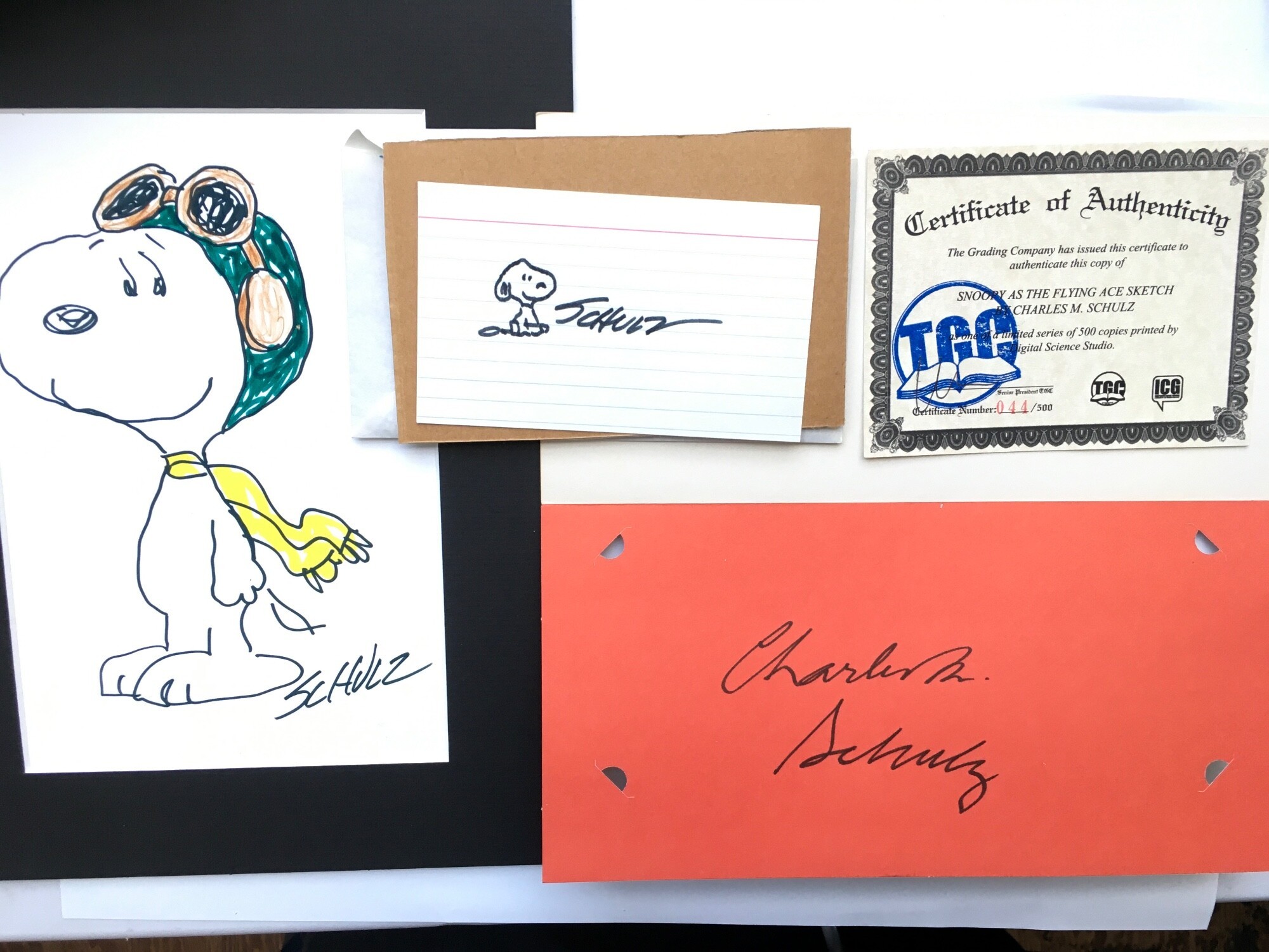 A Snoopy greetings card signed by Charles M Schulz, a small sketch of Snoopy signed by Schulz plus a limited edition print of Snoopy as The Flying Ace with COA.