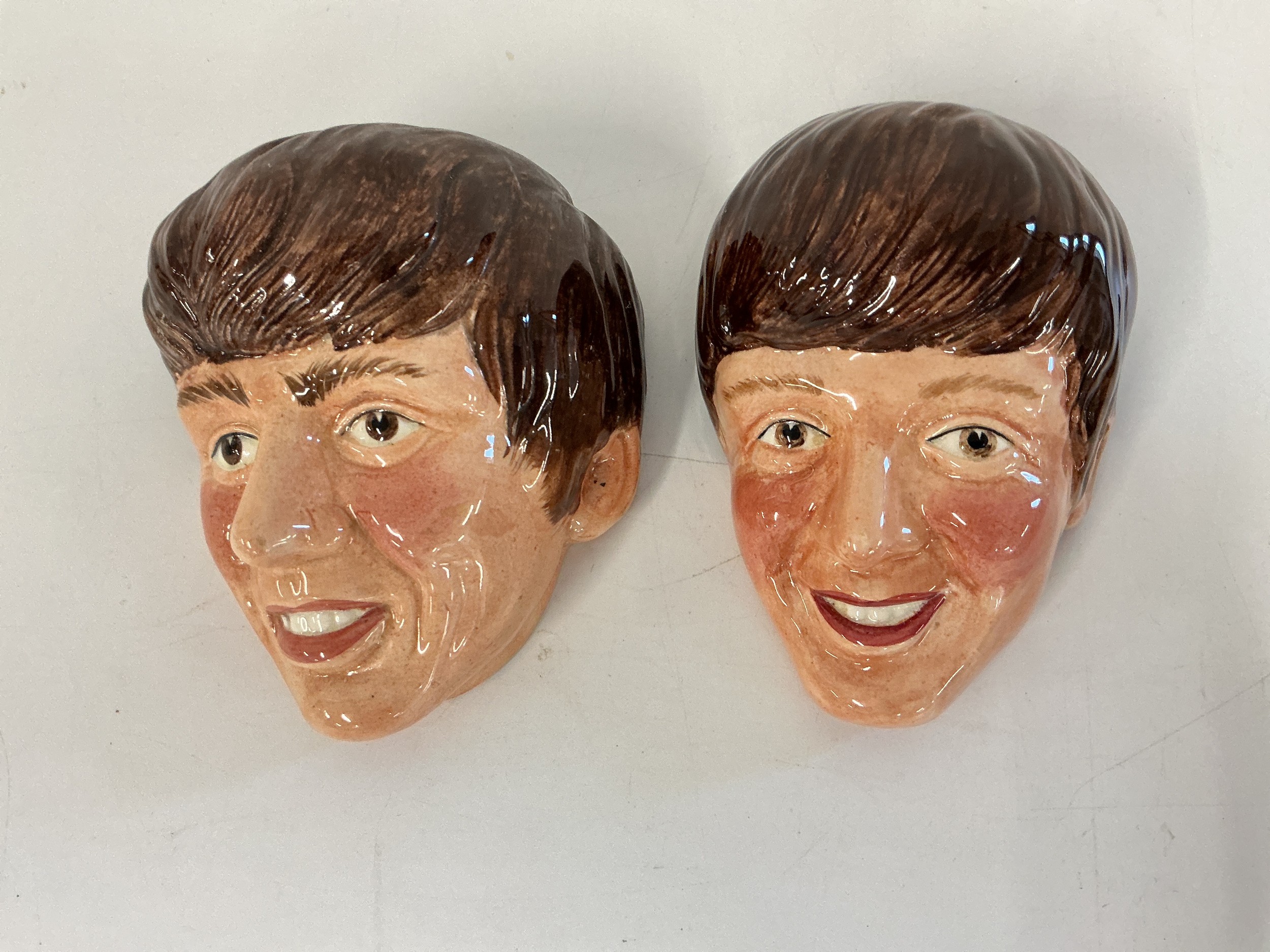 Two Kelsboro ware ceramic wall masks comprising one of John Lennon and one of George Harrison, approx height 12cm.