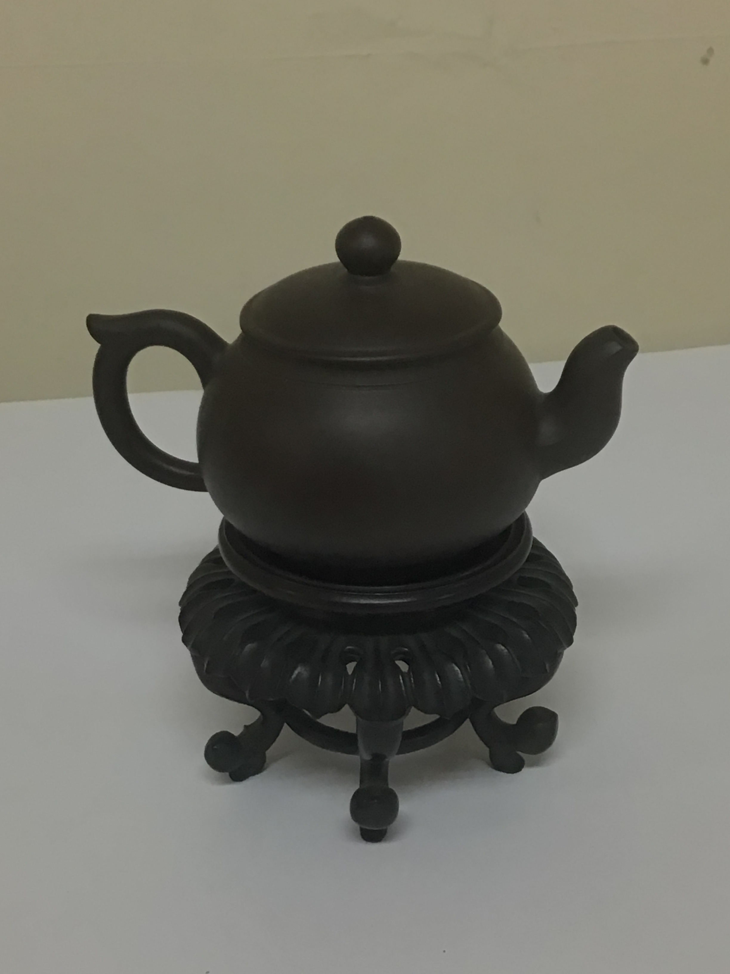  A minute Chinese earthenware tea pot on a hardwood stand the dark brown tea pot with caricature marks to the base no obvious damage. 