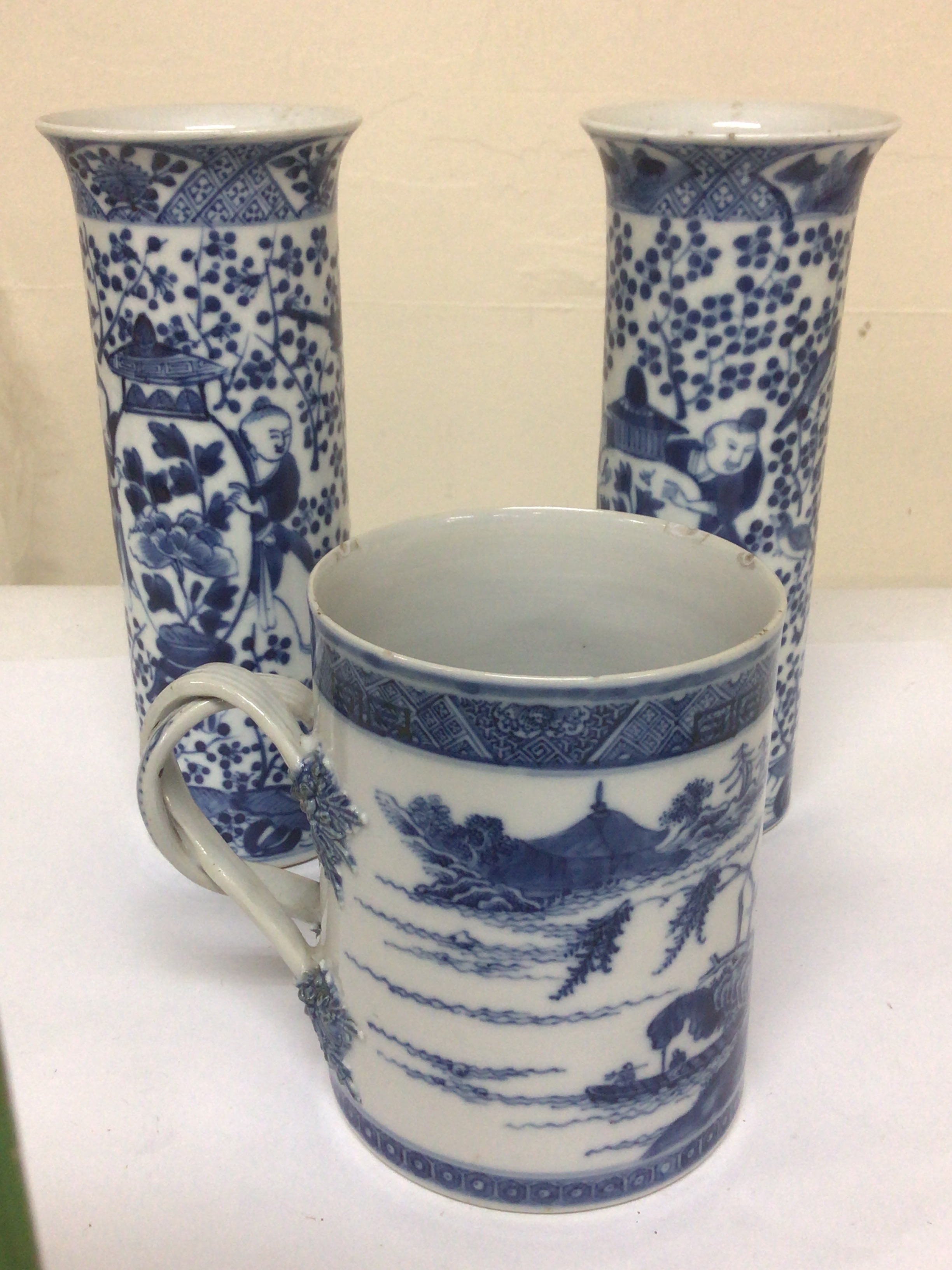 An 18th century Chinese export porcelain blue and white mug with intertwined handle 12cm and a pair of blue and white vases 19th century with caricature marks to the base. Height 21cm