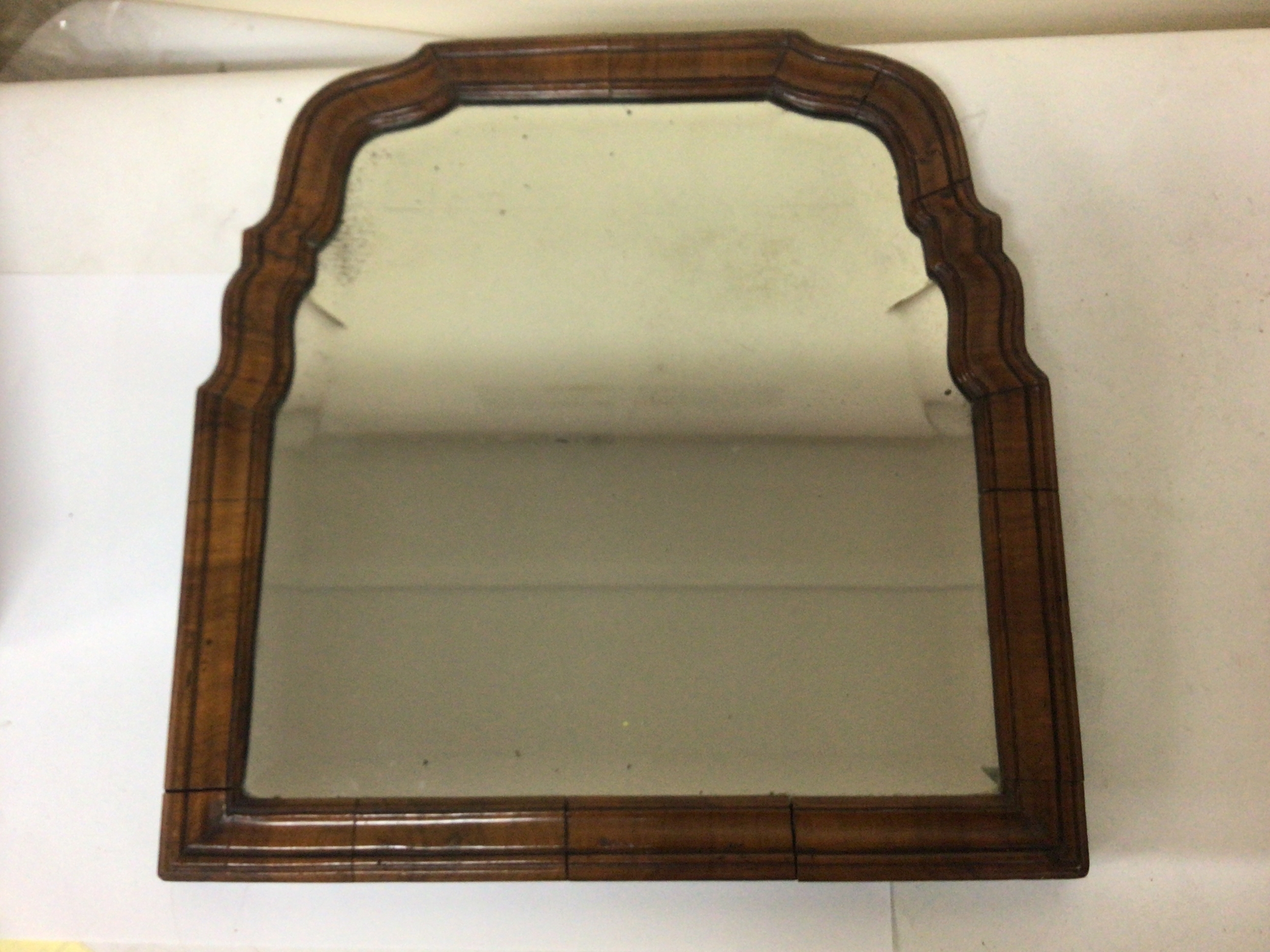 A George II 18th century walnut framed wall mirror with a shaped moulded edge 36cm wide 38cm approximately. With later alterations. replacement back