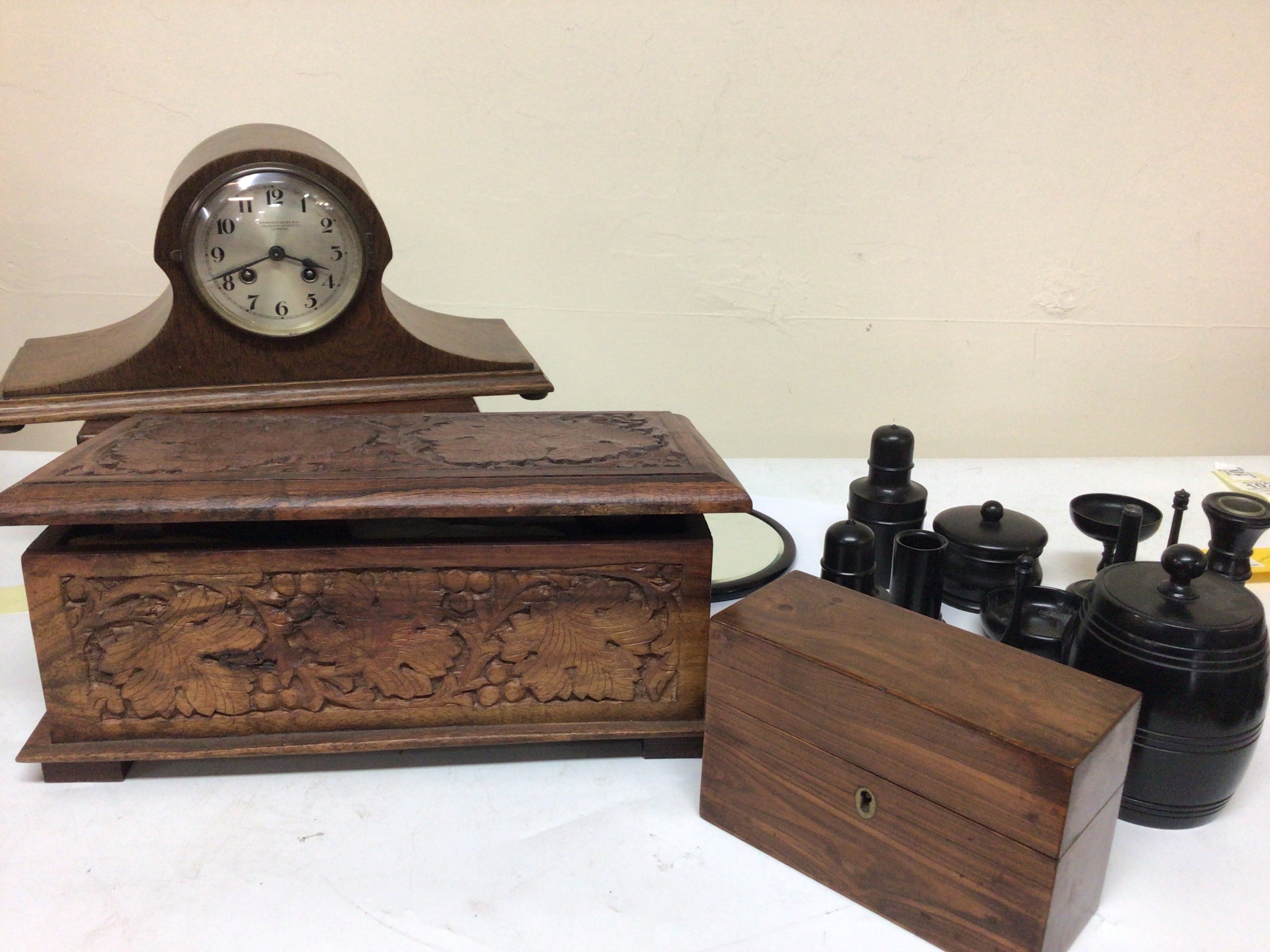  A Collection of ebony jars storage vessels a small barrel a carved box containing leather worker  or shoe makers vintage tools a small box possible Kingwood and an oak mantel clock maker Camrer Cuss. 