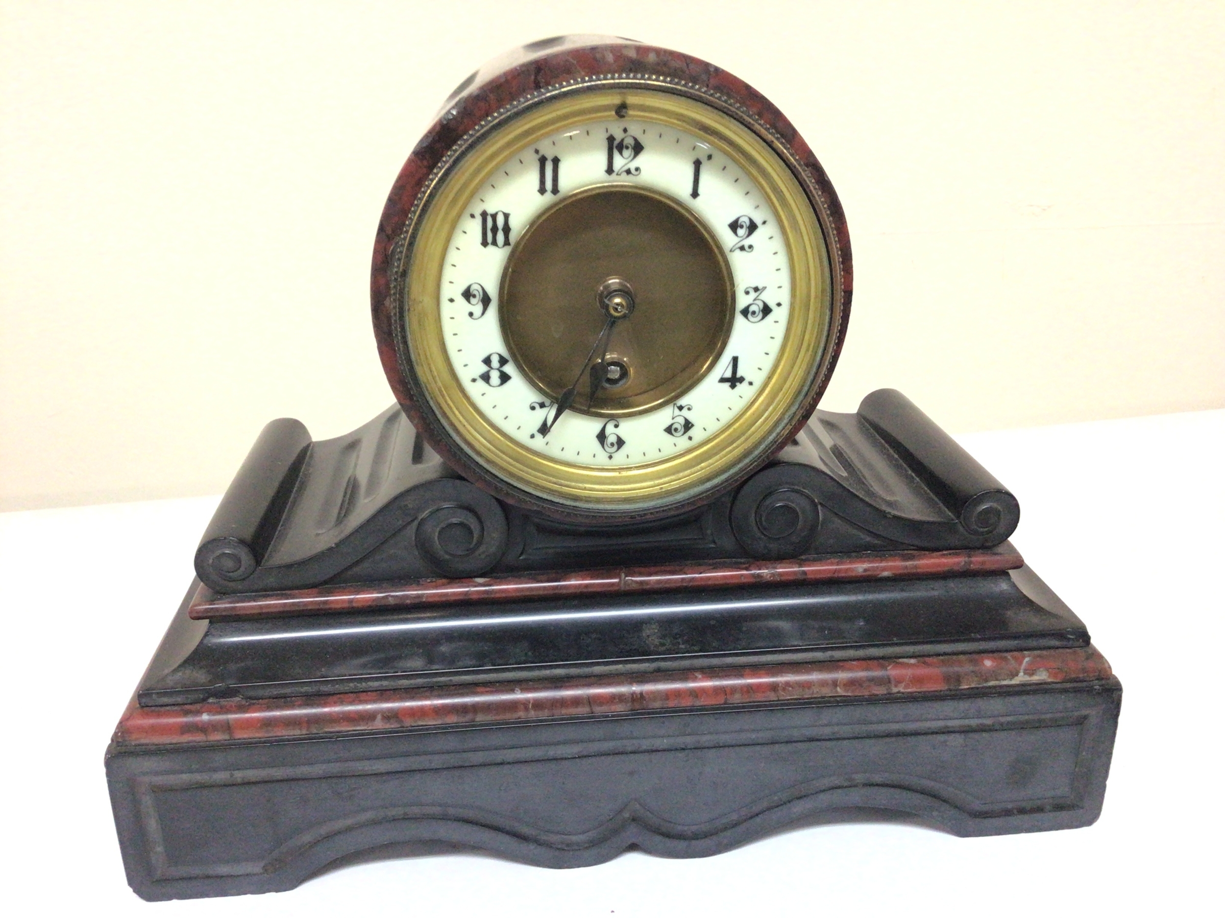  A black slate and marble Victorian mantel clock. 24cm high. Fitted with a French brass movement with pendulum. 
