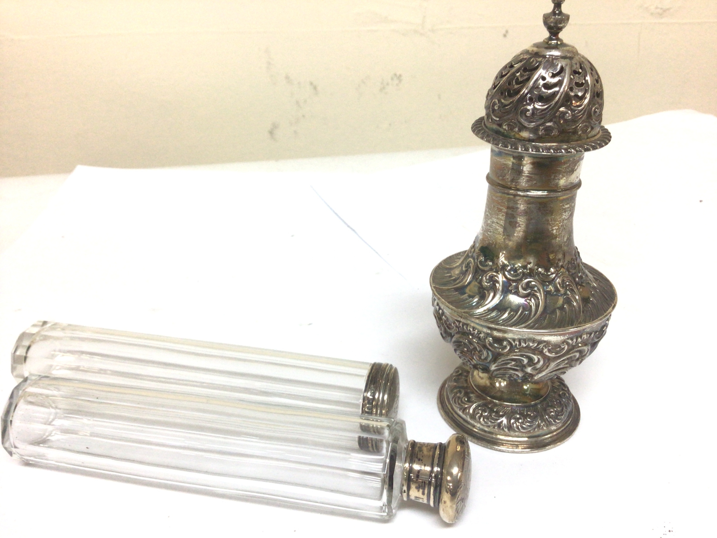  A silver sugar caster with Repousse scrolls Sheffield hallmarks weight 160g vand two silver topped glass jars 