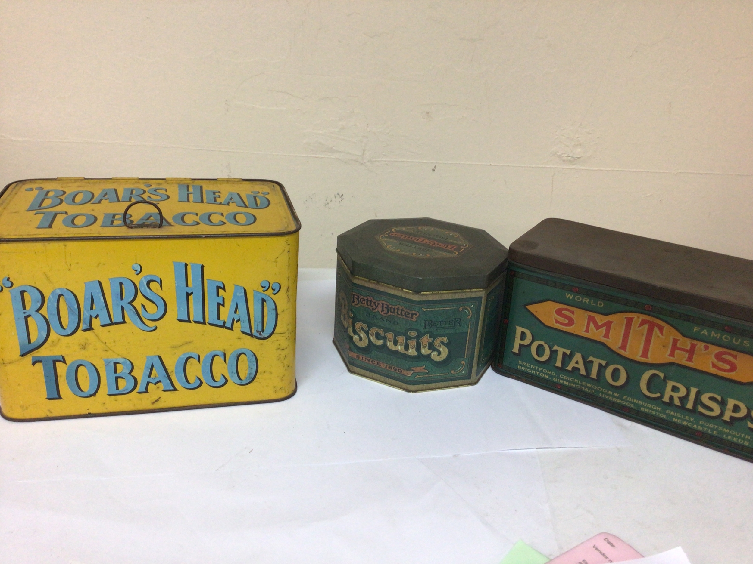  A box containing Vintage tins Smiths Crisps Boars Head Tobacco two vintage coffee grinders and other storage tins.