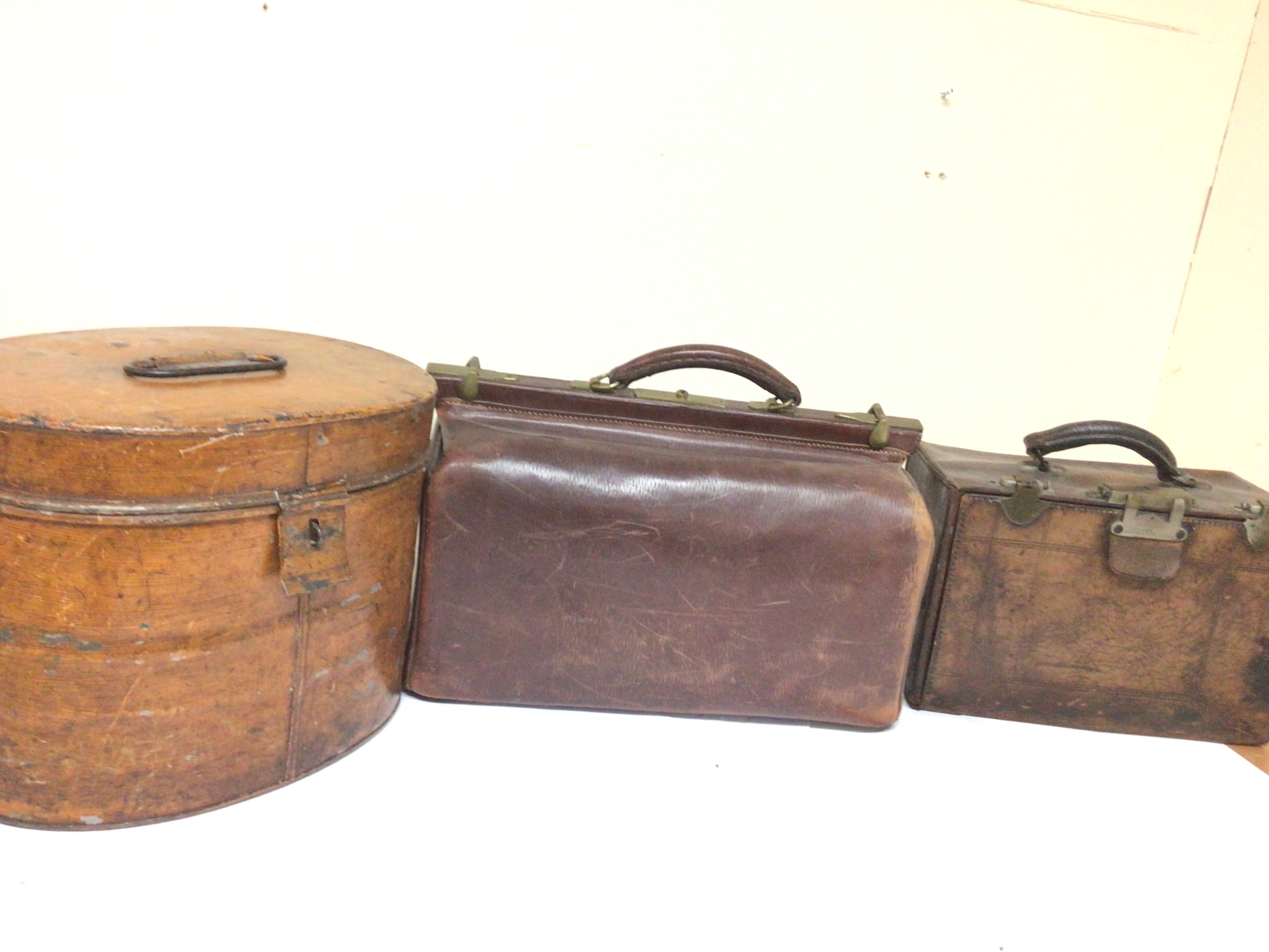 A Vintage leather Gladstone bag one other Vintage leather case and a Victorian tin hatbox. (3) 