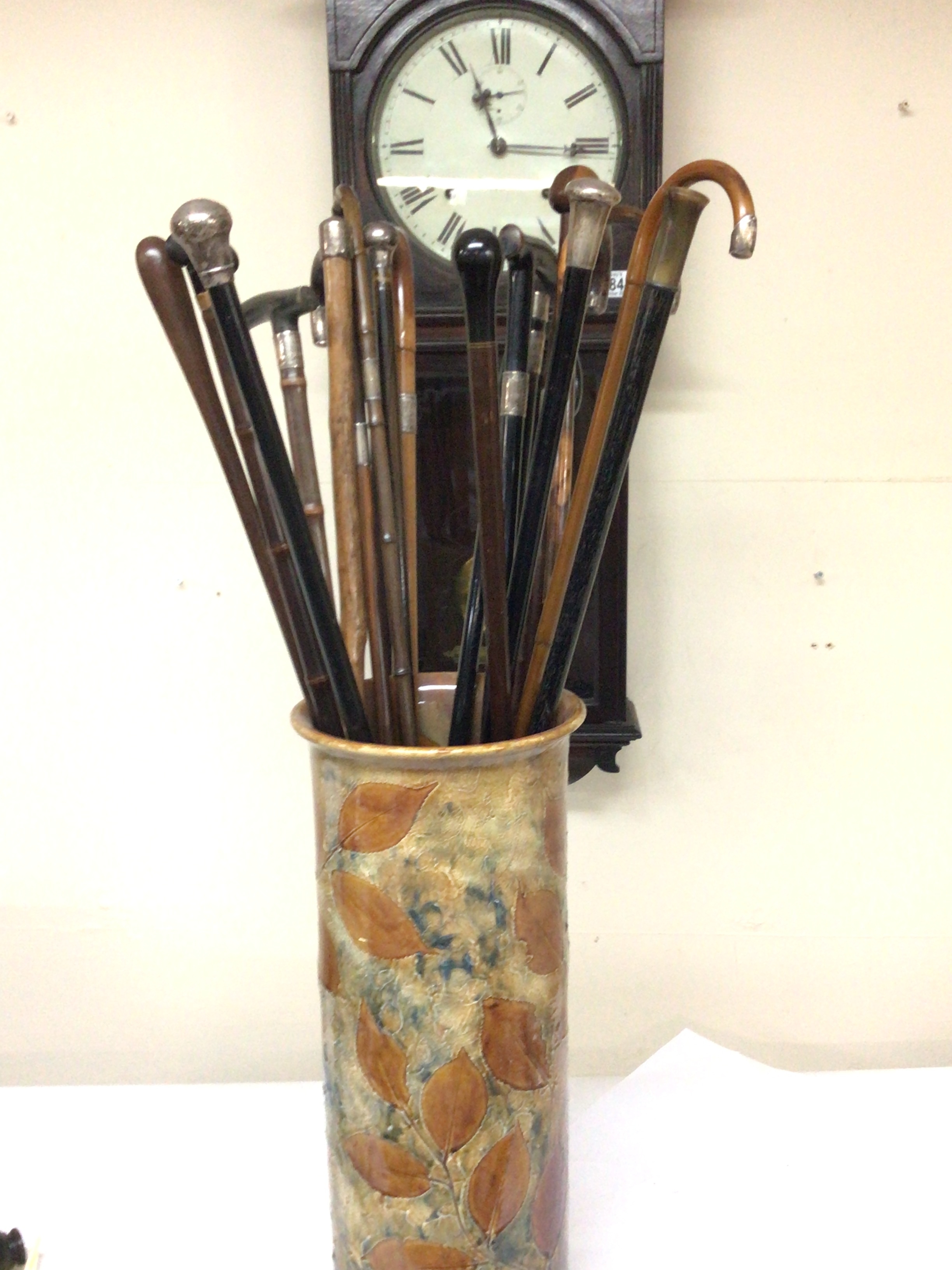  A Royal Doulton Stick stand containing a quantity of silver banded Victorian and later walking sticks 