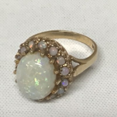 A 9carat gold ring set with a good sized opal flanked by smaller opals central stone with some surface cracks. Weight 4.9g